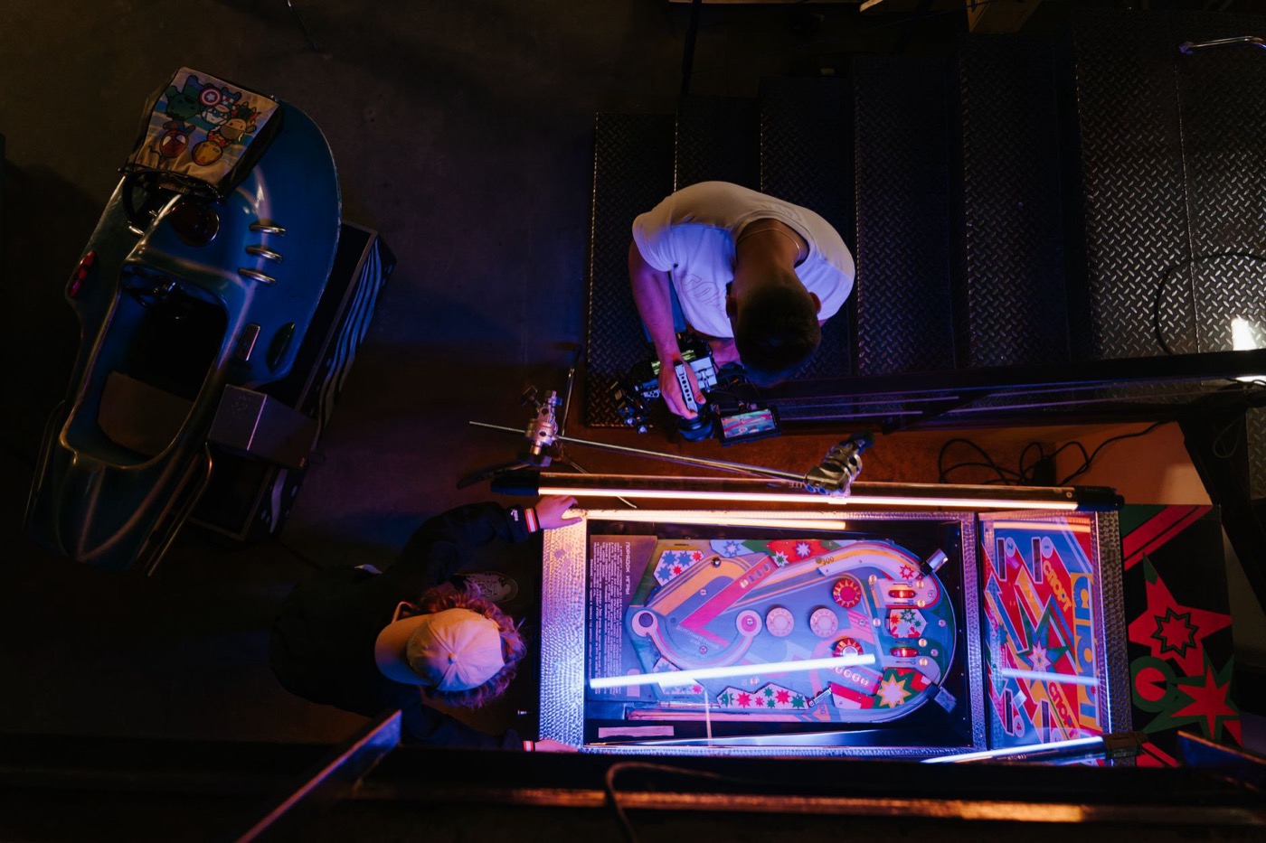Overhead view of pinball game being set up in a retro arcade setting.