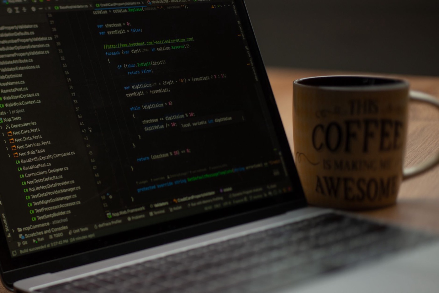 Close-up of a laptop screen with code and a coffee mug.