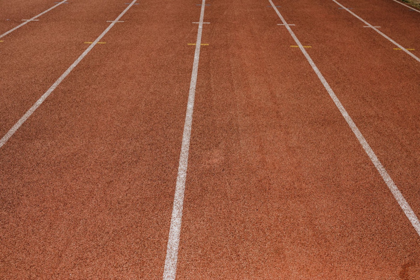 Empty red running track with marked lanes, ready for athletes.