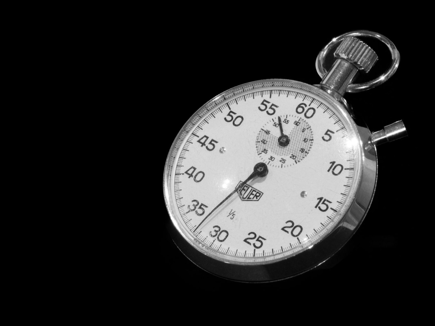 Vintage mechanical stopwatch with black dial against a dark background.